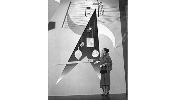 Image of a woman, designer Alma Shon, standing in front of an art piece