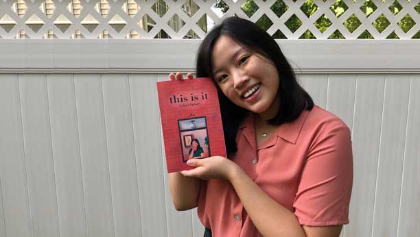 Calista Ogburn holding up her book of poetry