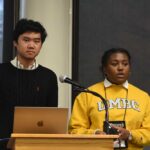 Two young students, one male and one female, presents their research to their peers.