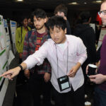 A young undergraduate researcher presenting his research to the public