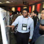 A young undergraduate researcher presenting his research to the public