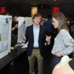 A young undergraduate researcher presenting his research to the public