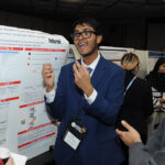 A young undergraduate researcher presenting his research to the public