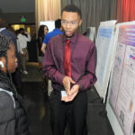 A young undergraduate researcher presenting his research to the public
