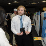 A young undergraduate researcher presenting his research to the public
