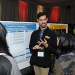 A young undergraduate researcher presenting his research to the public