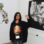 A young stduent research standing in front of her poster presentation