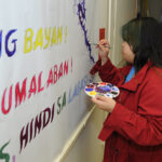 A young undergraduate researcher participating in a research event; she is painting a dragon