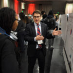 A young undergraduate researcher presenting his research to the public