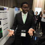 A young undergraduate researcher presenting his research to the public