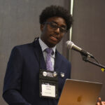 A young undergraduate researcher presenting his research to the public