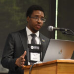 A young undergraduate researcher presenting his research to the public